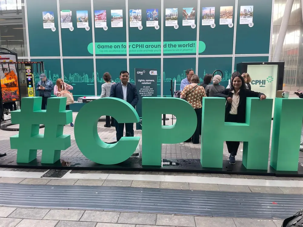 Team members beside the large green CPHI lettering at the entrance to the exhibition